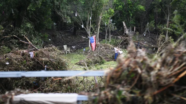 An American flag hangs over wreckage from the July 2025 floods in Texas